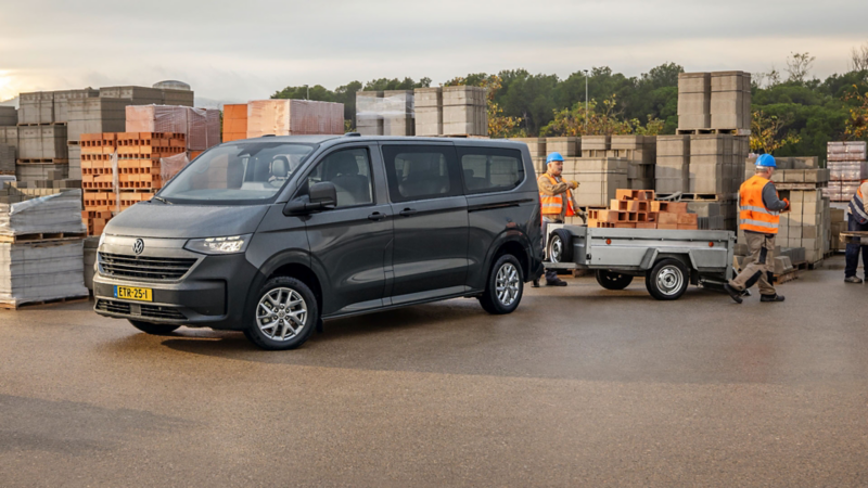 Nieuwe Volkswagen e-Transporter Kombi op bouwplaats met aanhangwagen