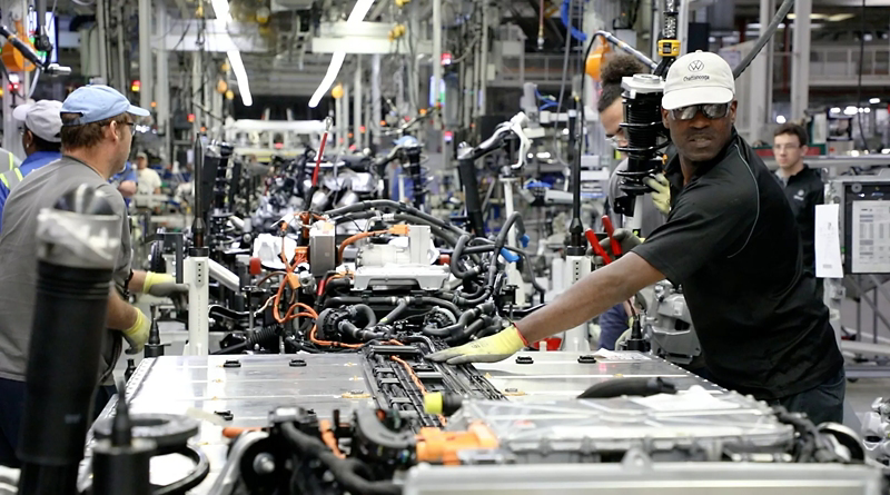 Empleados que trabajan diligentemente en la línea de montaje en las instalaciones de fabricación de Volkswagen Chattanooga, mostrando trabajo en equipo y precisión en la producción de vehículos.