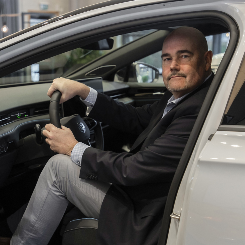 Bild av Johan Sjögren sittanden i förarsätet på en vit bil