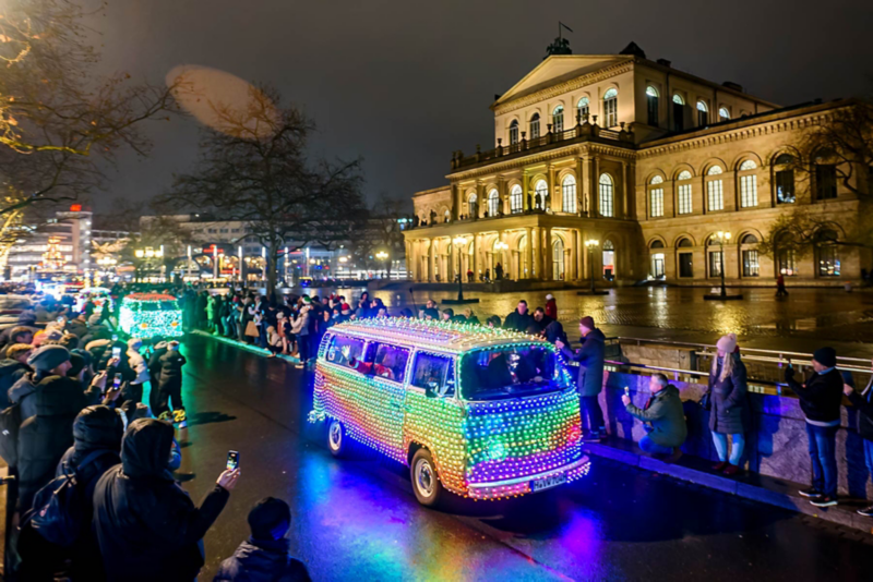 Illuminated Volkswagen Bulli in front of the opera house in Hanover being photographed by a crowd