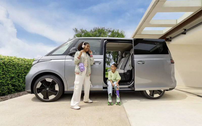 ID. Buzz geparkeerd op een oprit met twee kinderen erbij waarvan er één staat en de ander in zit in de deuropening van de ID. Buzz