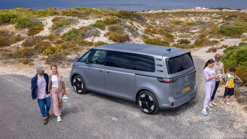 ID. Buzz geparkeerd aan zee met een gezin ernaast