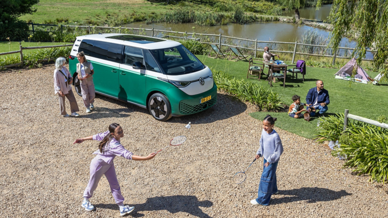 ID. Buzz geparkeerd op een picknick plek met een gezin dat van het mooie weer aan het genieten is