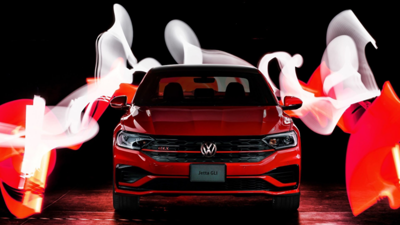 Hombre parado junto al auto deportivo Jetta GLI de Volkswagen en color rojo tornado