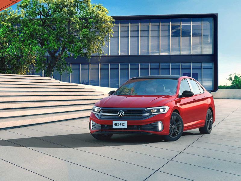 Nuevo Jetta 2022. Auto familiar sedán Volkswagen en color rojo estacionado en una plaza.