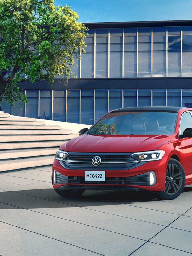 Nuevo Jetta 2022. Auto familiar sedán Volkswagen en color rojo estacionado en una plaza.