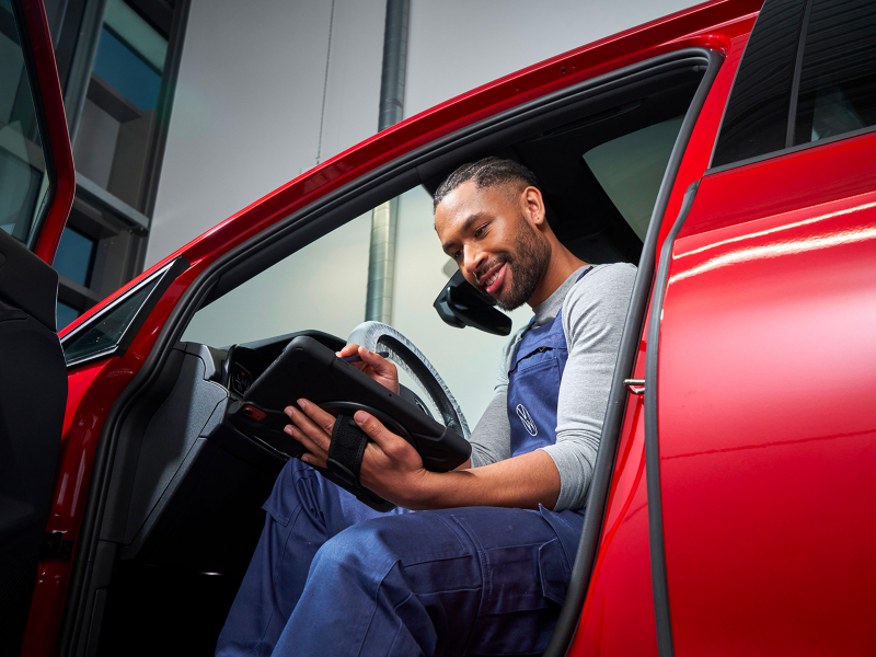 VW service employee in a VW car looks at a tablet – Volkswagen Service