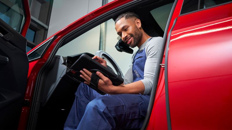 VW service employee in a VW car looks at a tablet – Volkswagen Service