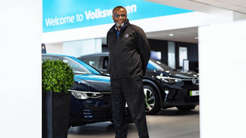 a man standing outside a VW dealership