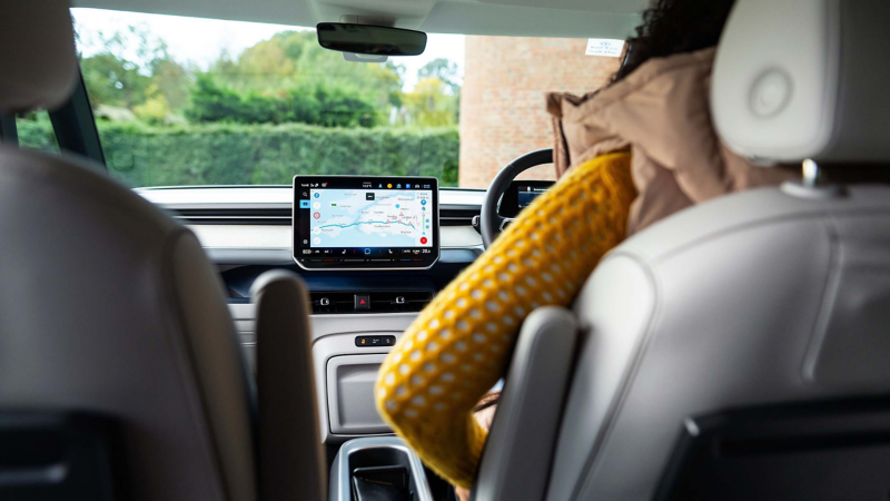 Driver using Volkswagen infotainment navigation system inside vehicle cabin.
