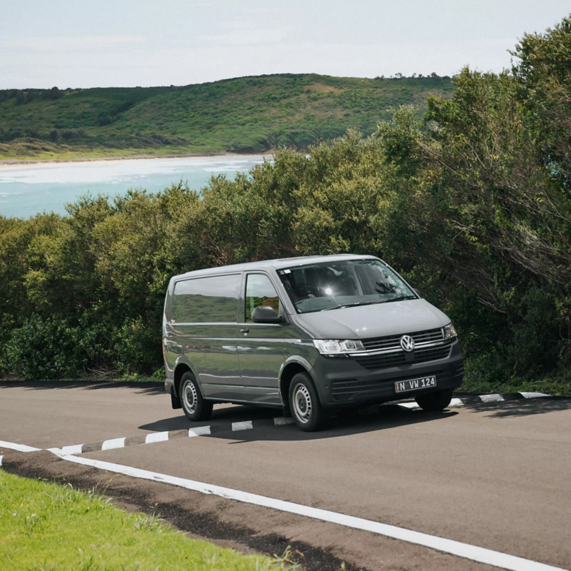 Transporter Van driving over speed bump with beach in the background