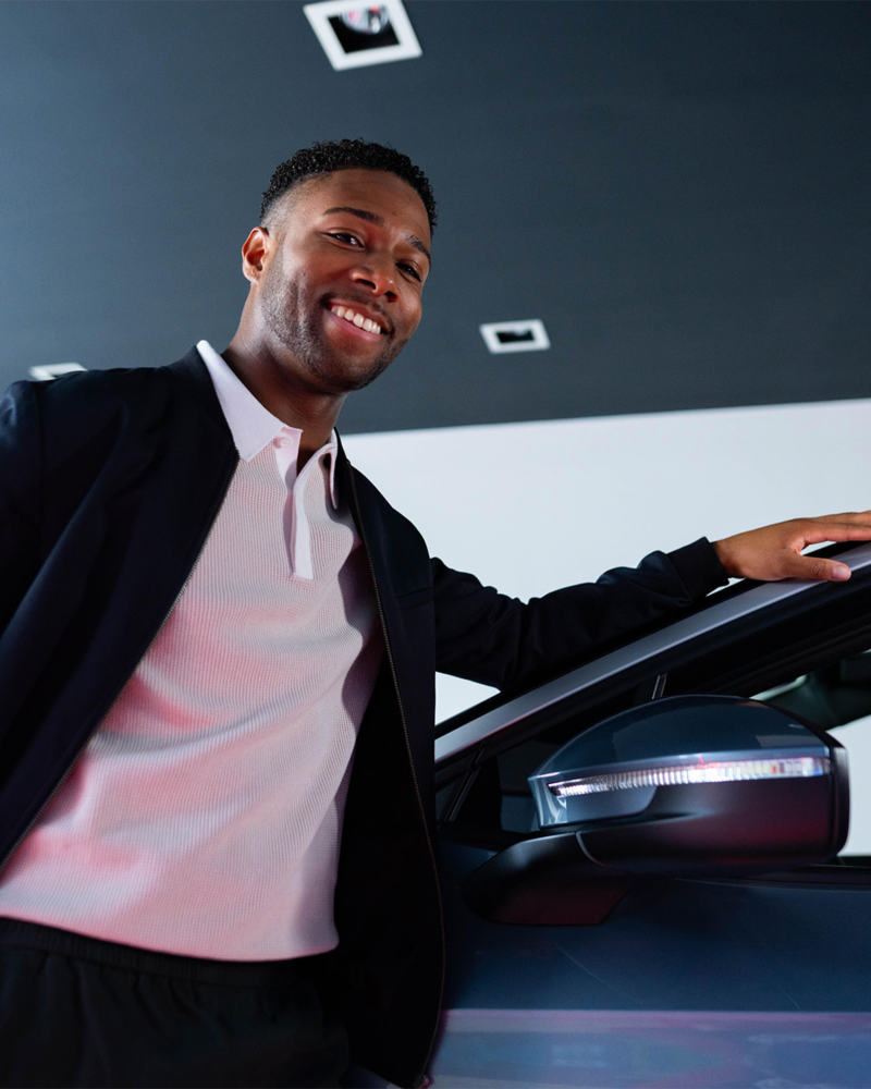 A VW retailer employee leaning on an ID.7 and facing towards the camera