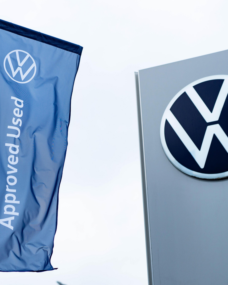 An image of a Volkswagen sign with an Approved Used flag next to it