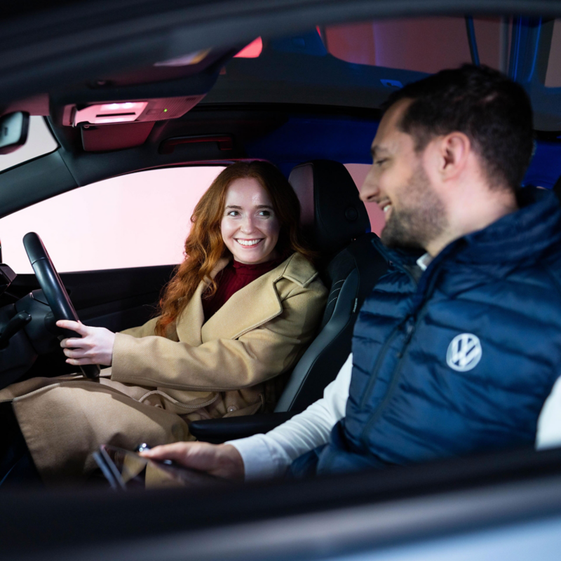 A VW retailer employee showing a customer the front cockpit