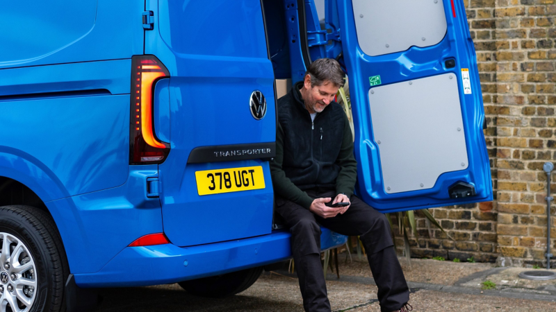 Person using their mobile in a parked VW Transporter.