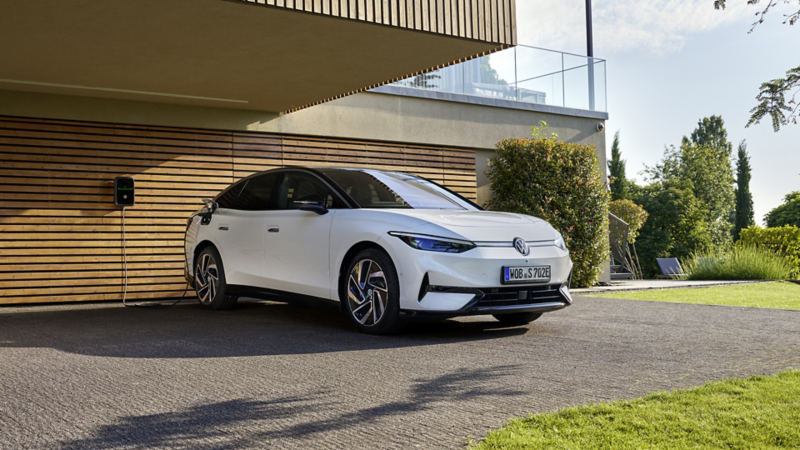 Ein ID.7 Tourer steht vor einem modernen Wohnhaus und lädt an einer Wallbox.