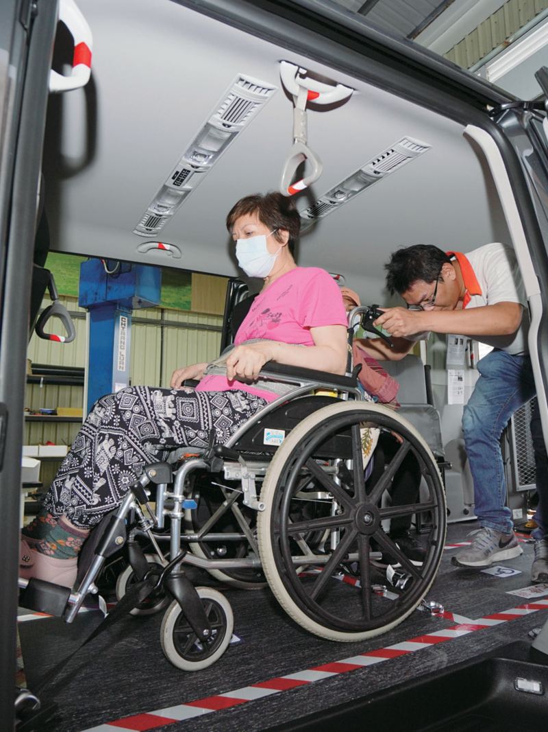男性正準備將在坐在輪椅上的女性小心的推下車(車款為珍珠黑色的Caravelle IPC )