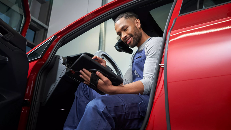 Volkswagen monteur kijkt naar een tablet in een Volkswagen in de werkplaats