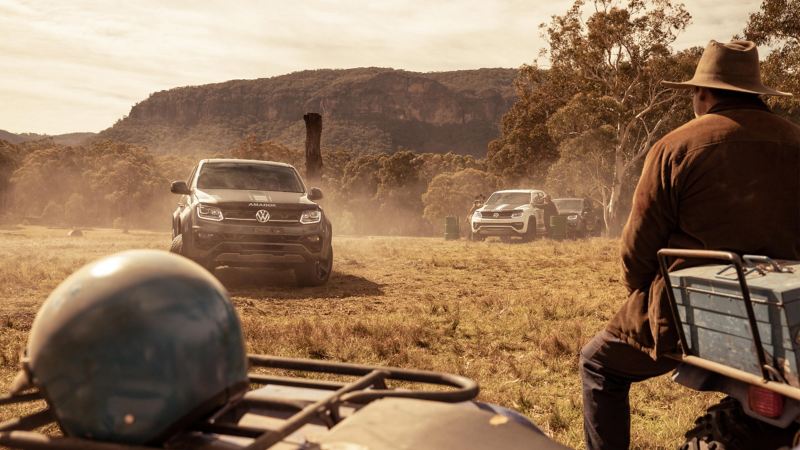 Volkswagen Amarok W-Series driving on paddock with farmer sitting on quadbike in foreground.