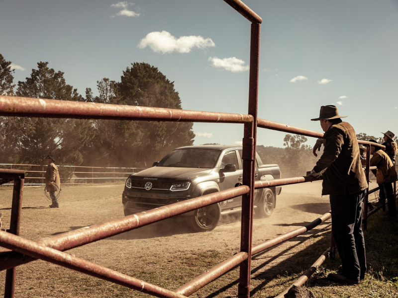 Volkswagen Amarok W-Series drifting in paddock with farmers watching behind fence.