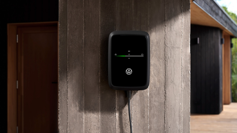 Detailansicht einer VW Wallbox ID. Charger Connect 2 mit grüner Ladeanzeige an einer Hauswand.