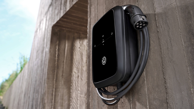 Volkswagen electric vehicle wall charger mounted on an exterior concrete wall.