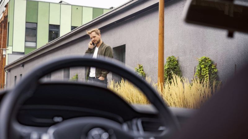Un homme tenant un téléphone devant une voiture Volkswagen