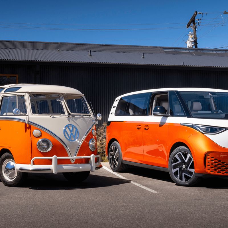 Un ID.Buzz orange garé devant un VW Microbus orange