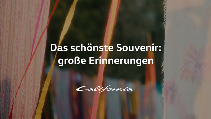 Schriftzug "Das schönste Souvenir: große Erinnerungen" vor bunten Fähnchen im Wind.