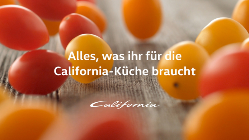Rote und gelbe Cocktailtomaten fallen auf einen Tisch.