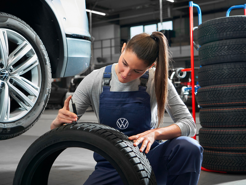 VW service employee checks profile of a VW tyre