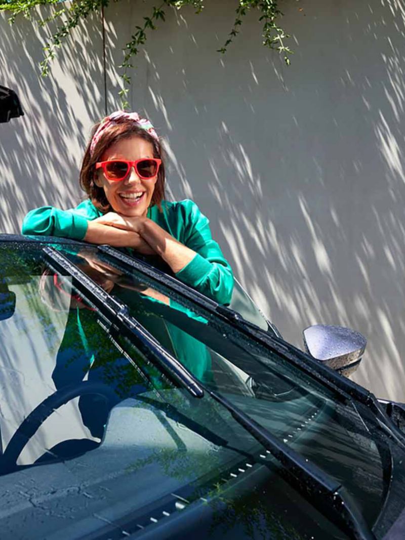 Una donna sorridente appoggiata all'auto.