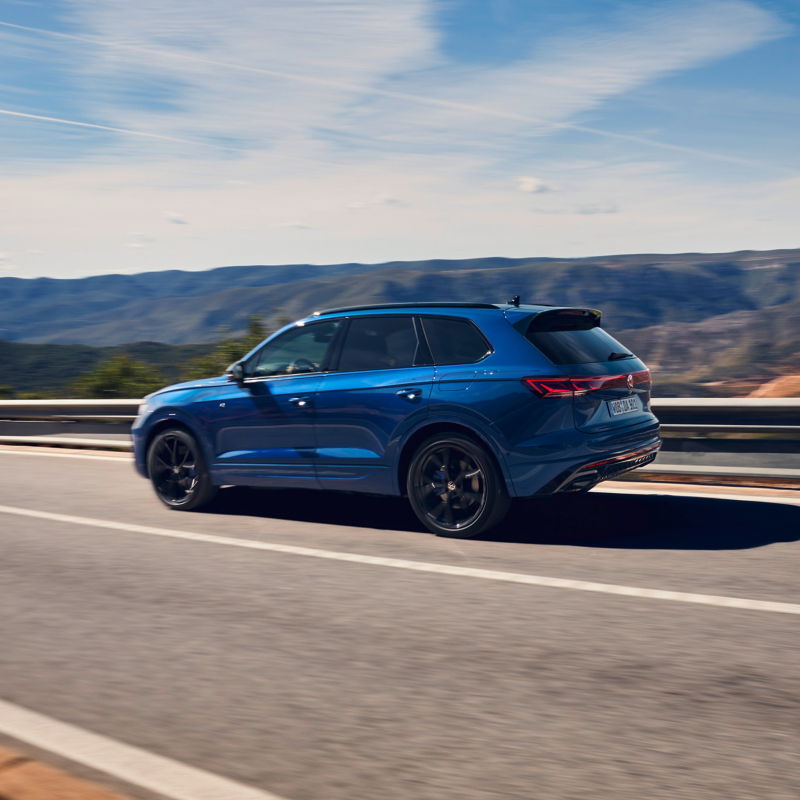 Blue Touareg R PHEV SUV driving in the sun along open road