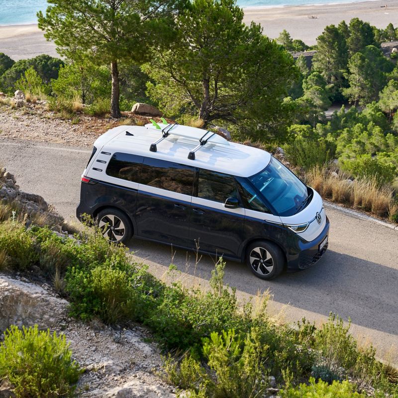 VW ID. Buzz with surfboard on roof takes a curve