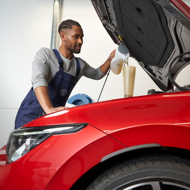 VW Servicemitarbeiter füllt Öl nach – Ölwechsel Service