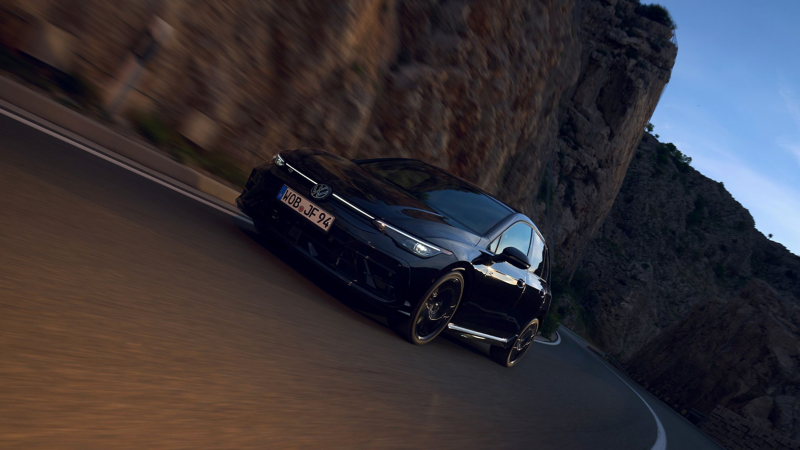 Nowy Golf R Black Edition jedzie drogą w górzystym krajobrazie. 