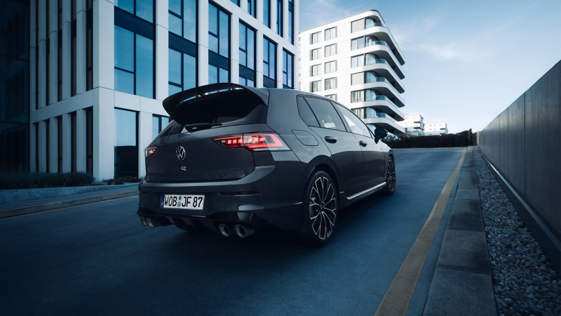 Vue arrière d’une VW Golf R garée devant un garage ouvert; un homme est à côté
