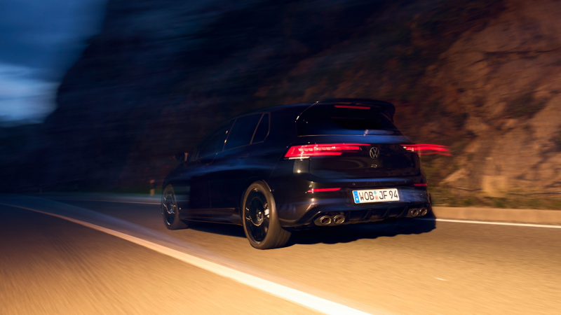 Ένα VW Golf R Black Edition κινείται σε ορεινό δρόμο με αναμμένα, θολά πίσω φώτα