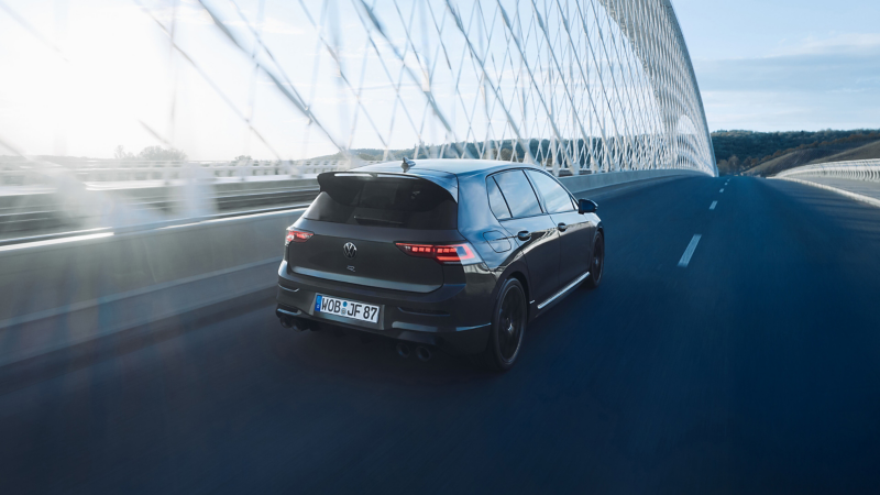 Ένα VW Golf R στον δρόμο το σούρουπο. Οι προβολείς και η φωτεινή λωρίδα LED είναι αναμμένα.