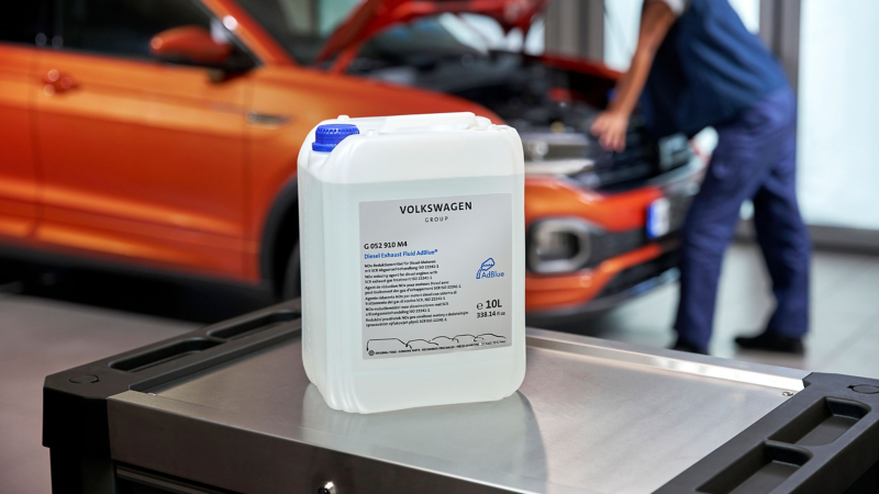 Ad Blue in a mechanics workshop with a car being repaired in the background 