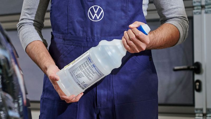 VW service employee holds a bottle of AdBlue® in his hand