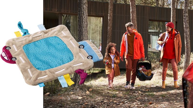 VW Baby-Kuscheltuch, im Hintergrund ein junges Paar mit zwei Kindern