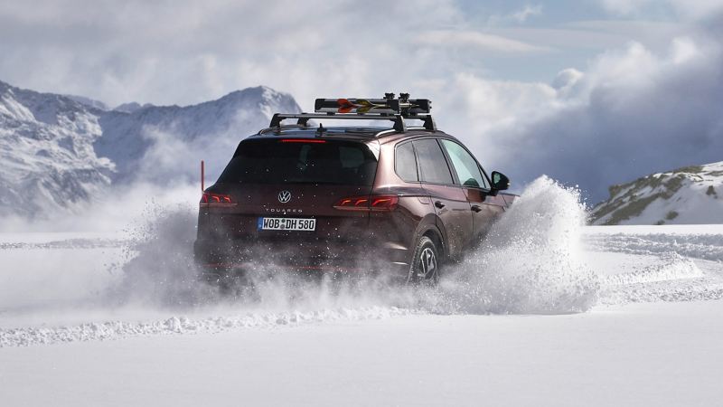 Ein Touareg im Schnee, mit einem Skihalter von Volkswagen Zubehör ausgestattet, transportiert zwei Paar Ski