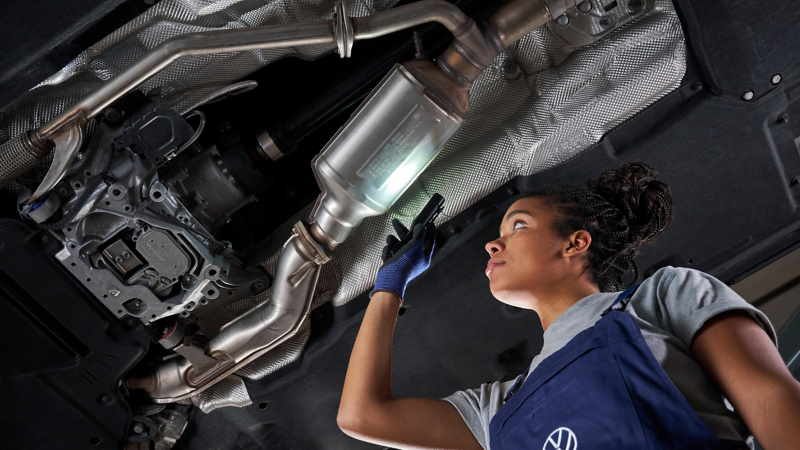 VW service employee inspects the diesel particulate filter of a VW car