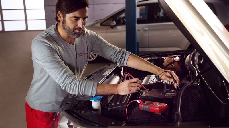 Een servicemedewerker van VW controleert de batterij van een auto in het kader van een Economy Service
