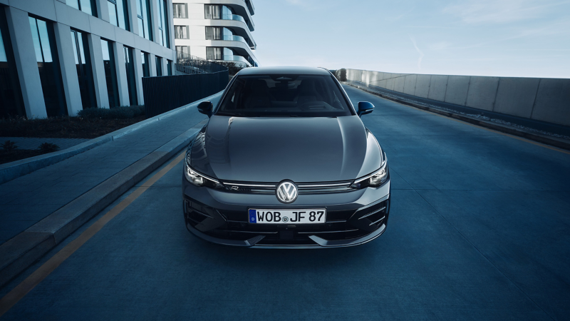 Un homme appuyé contre une Golf R bleue, focus sur la vue arrière de la voiture.