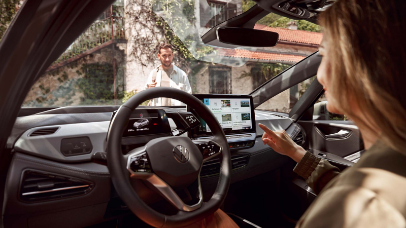 Frau nutzt In-Car App Fahrzeugservice im VW Infotainment-System.