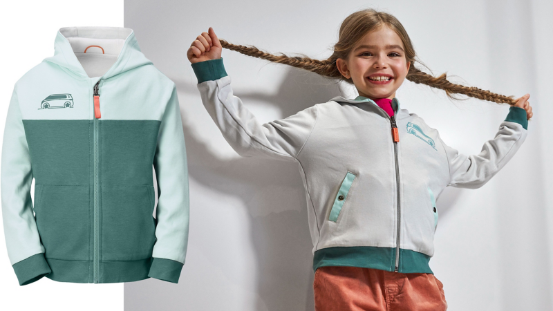 Mädchen freut sich über Wendejacke aus der ID. Buzz Kollektion und zieht ihre Zöpfe lang