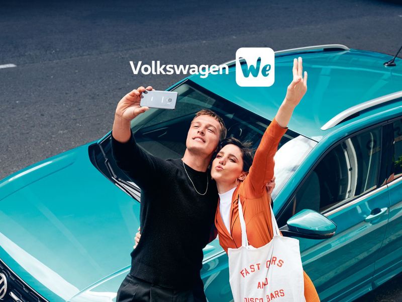 Ein Pärchen macht ein Selfie vor einem türkisenen VW T-Cross