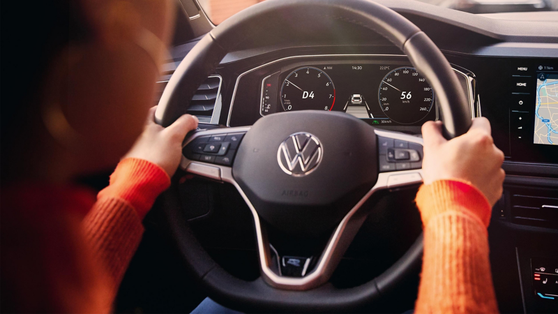View of a person holding the steering wheel of a VW Polo in their hands